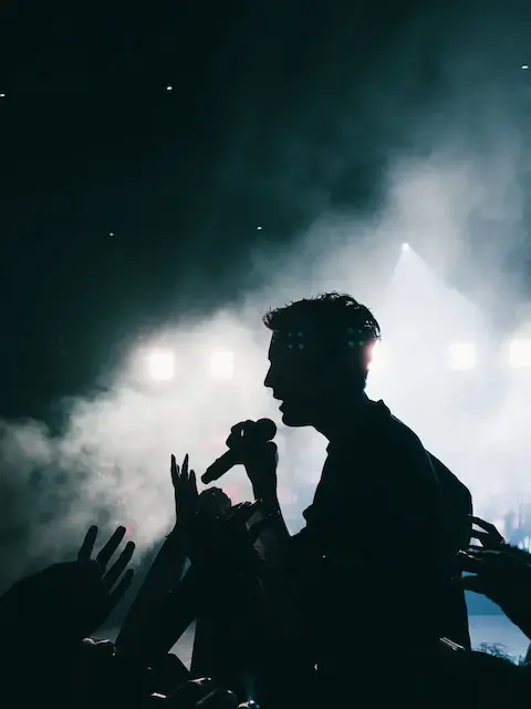 a side profile silhouette of an artist holding a microphone in a concert